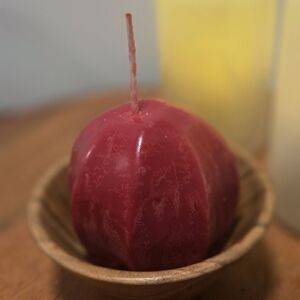 Red Pumpkin-Shaped Candle In A Small Wooden Bowl